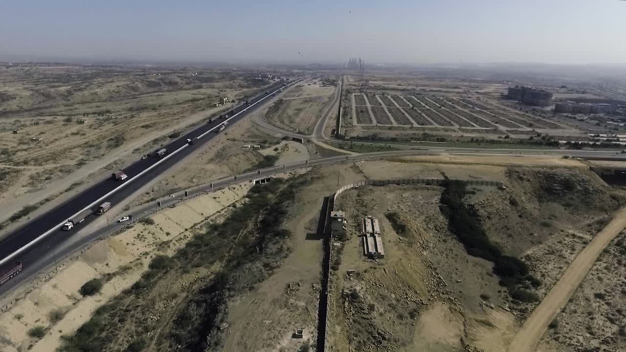 una vista aérea en cámara lenta de una carretera y una ciudad, los arrastreros pesados y los coches se mueven por la carretera, se conecta un intercambio