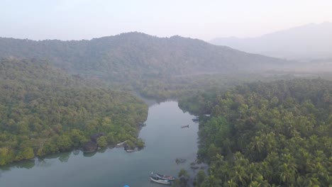 Boote-Vertäut-Auf-Ruhigem-Wasser-Mit-Zotteligen-Wäldern-Und-Bergketten-Im-Hintergrund-Während-Eines-Dunstigen-Morgens-In-Palolem-Beach,-Canacona,-Süd-Goa,-Indien