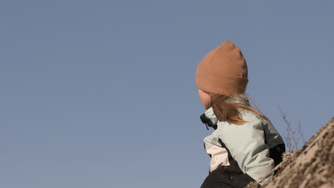 Young-blonde-Caucasian-girl-on-hill,-looks-into-distance