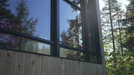 hamaca colgada dentro de una casa forestal junto a la ventana de cristal con reflejo