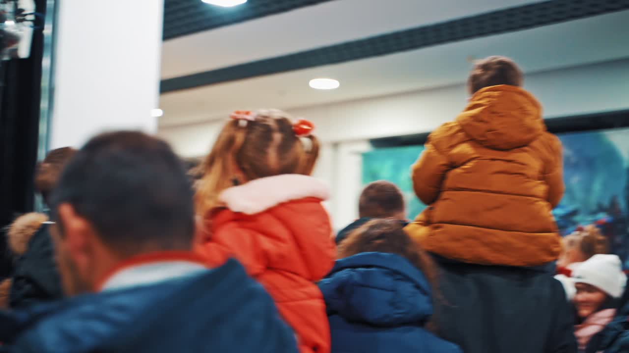 Anak duduk di pundak orang tua. Kerumunan orang di festival. Orang-orang melihat.