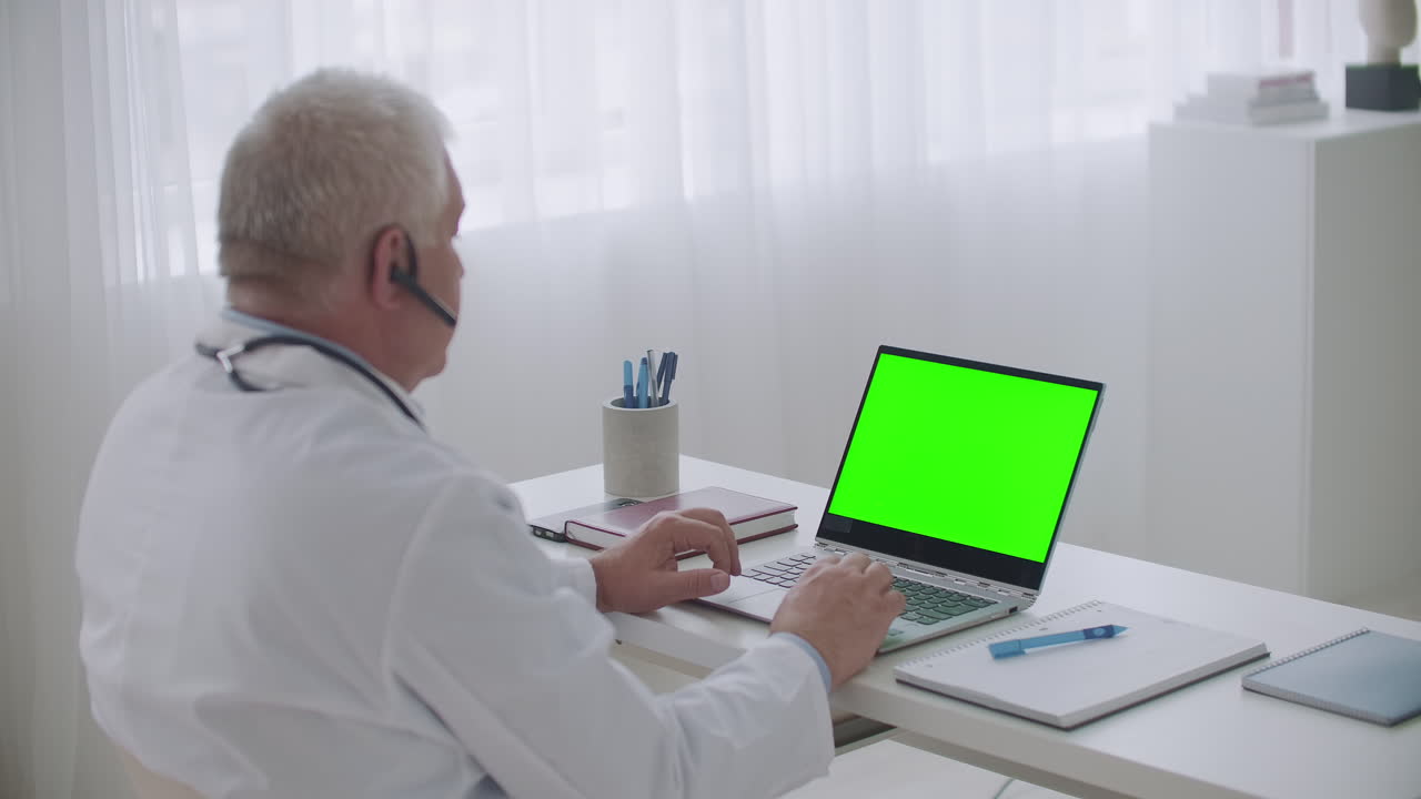 conferencia médica en línea médico masculino está viendo y escuchando webinar en portátil con pantalla verde para tecnología de clave de croma modo de trabajo remoto