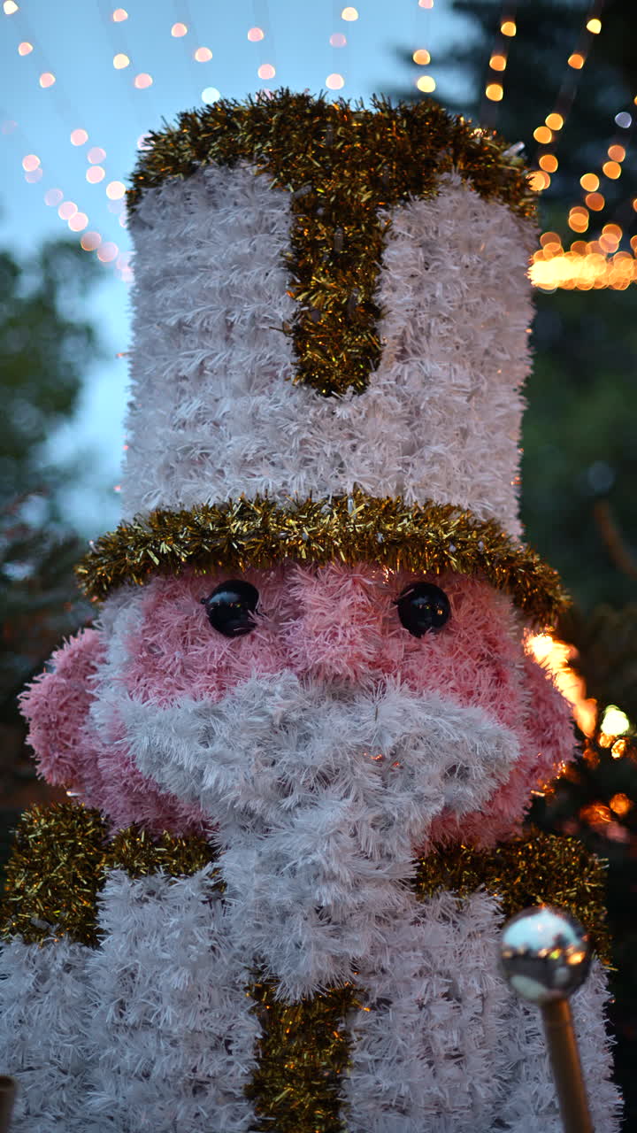 Decorative Christmas nutcracker soldier figure displayed outdoors with trees in the background. Vertical