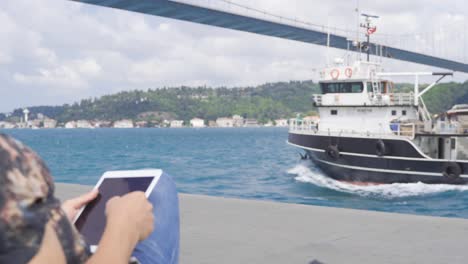 hombre alegre trabajando en su tabla contra el mar en la ciudad.