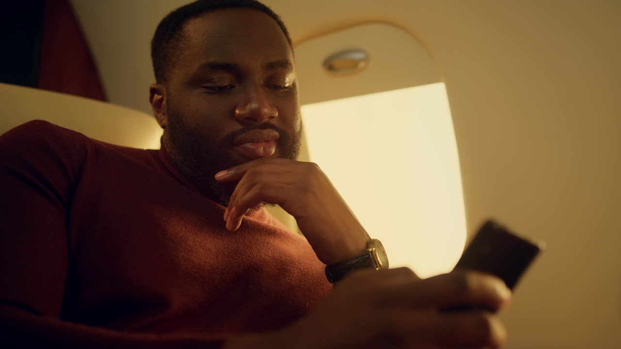 ⁇ 드폰을 클로즈업으로 사용하는 사려 깊은 남자. 즐거운 승객이 온라인으로 전화를 검색하고 있습니다.