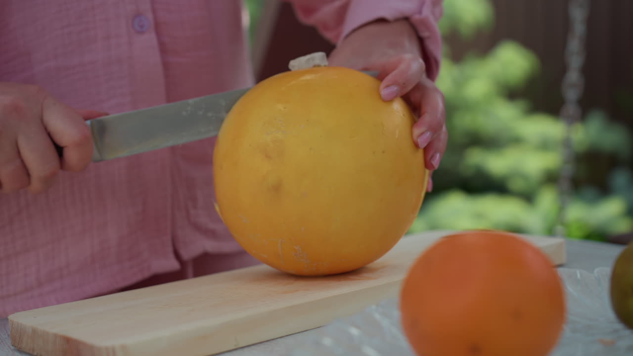 Caucasian Hands Prepare Melon Slices, Persons Carefully Cut Open Fresh Melon Revealing Seeds And Pulp, Detailed View Of Hands Slicing Ripe Melon On Cutting Board During Summer Garden Activity