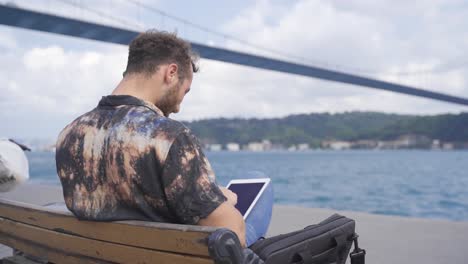 Young-man-working-with-tablet-and-talking-on-phone.