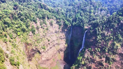 aerial view of tad fane waterfall in pakse, laos, with twin streams plunging into a lush forested gorge, surrounded by dense jungle and steep cliffs, highlighting the area's dramatic elevation drop