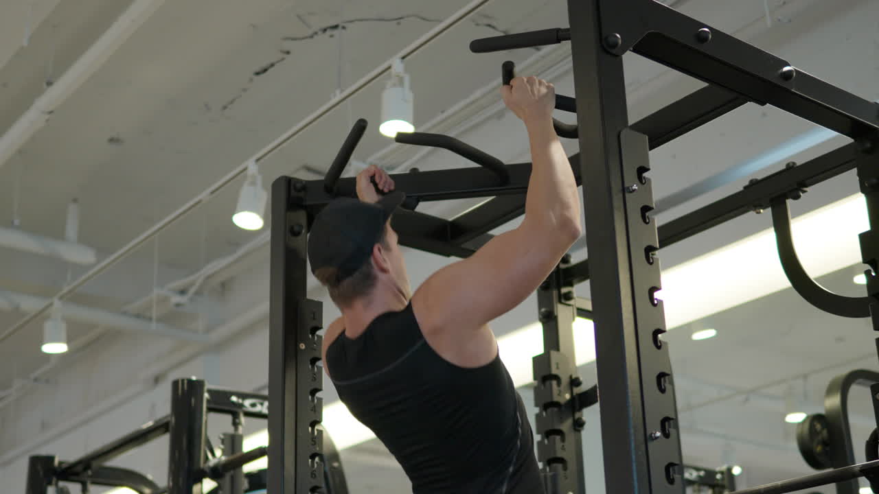 hombre de fitness bombeando músculos haciendo ejercicios de pull-ups en el gimnasio - ángulo bajo cámara lenta