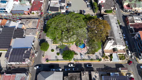 Paneles-Solares-Modernos-En-El-Techo-Del-Edificio-Al-Lado-Del-Parque-Con-La-Iglesia-En-La-Ciudad-De-Jarabacoa,-República-Dominicana