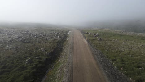 Tauchen-Sie-Mit-Dieser-Drohnenaufnahme-In-Geheimnisse-Ein-Und-Navigieren-Sie-über-Eine-Unbefestigte-Straße-Auf-Einem-Berg,-Die-Im-Nebel-Verschwindet,-Während-Der-Weg-Vor-Ihnen-Verborgen-Ist-Und-Unsichtbare-Wunder-Verspricht