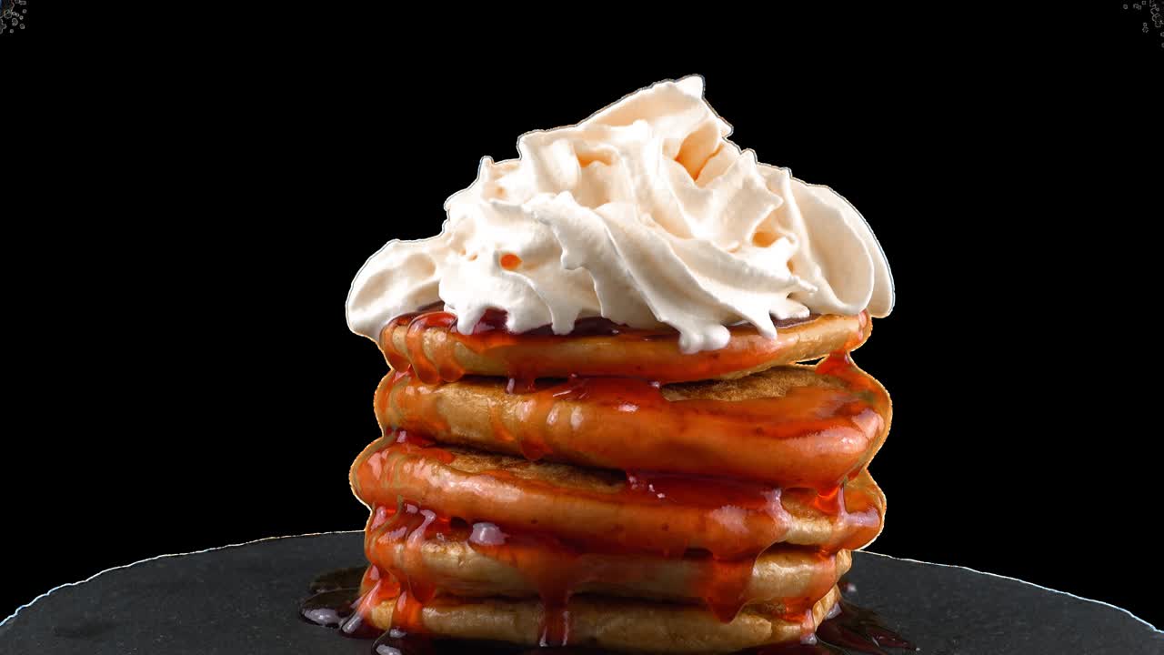 Pancakes with strawberry topping and whipped cream. Pancake lies on a black slate round stone. Alpha channel included.