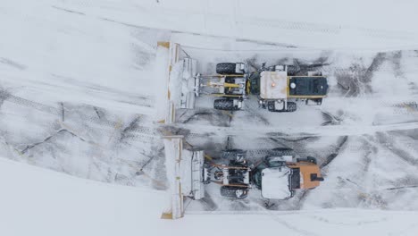 couple of snow plow machines in action of removing snow covered parking lot. drone view.