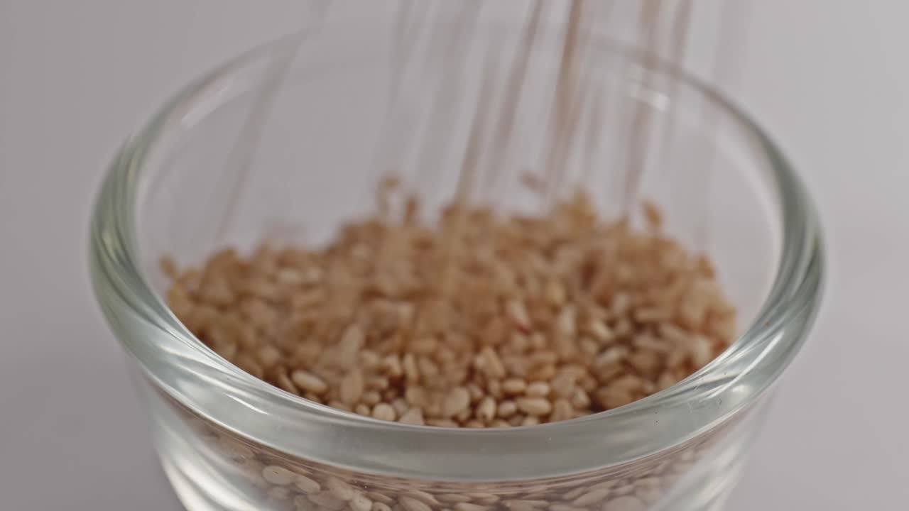 sesame seeds falling in small glass bowl, 4k, stable shot