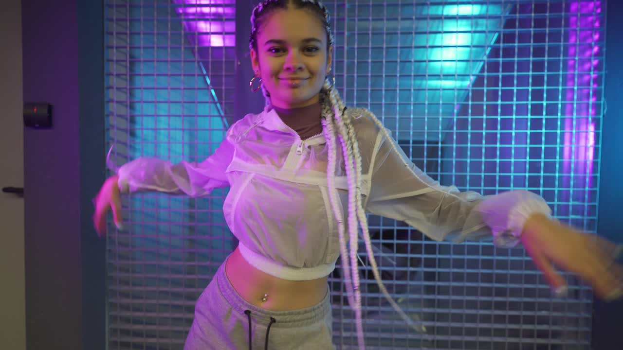 Woman with braids dancing in neon-lit urban setting