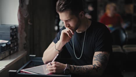 tattoo artist  designing motifs on digital tablet