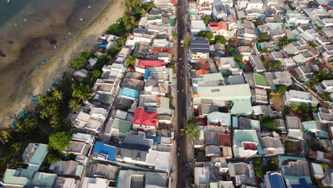 Aerial,-densely-packed-village-houses-next-to-beach-coast-in-Mui-Ne,-Vietnam
