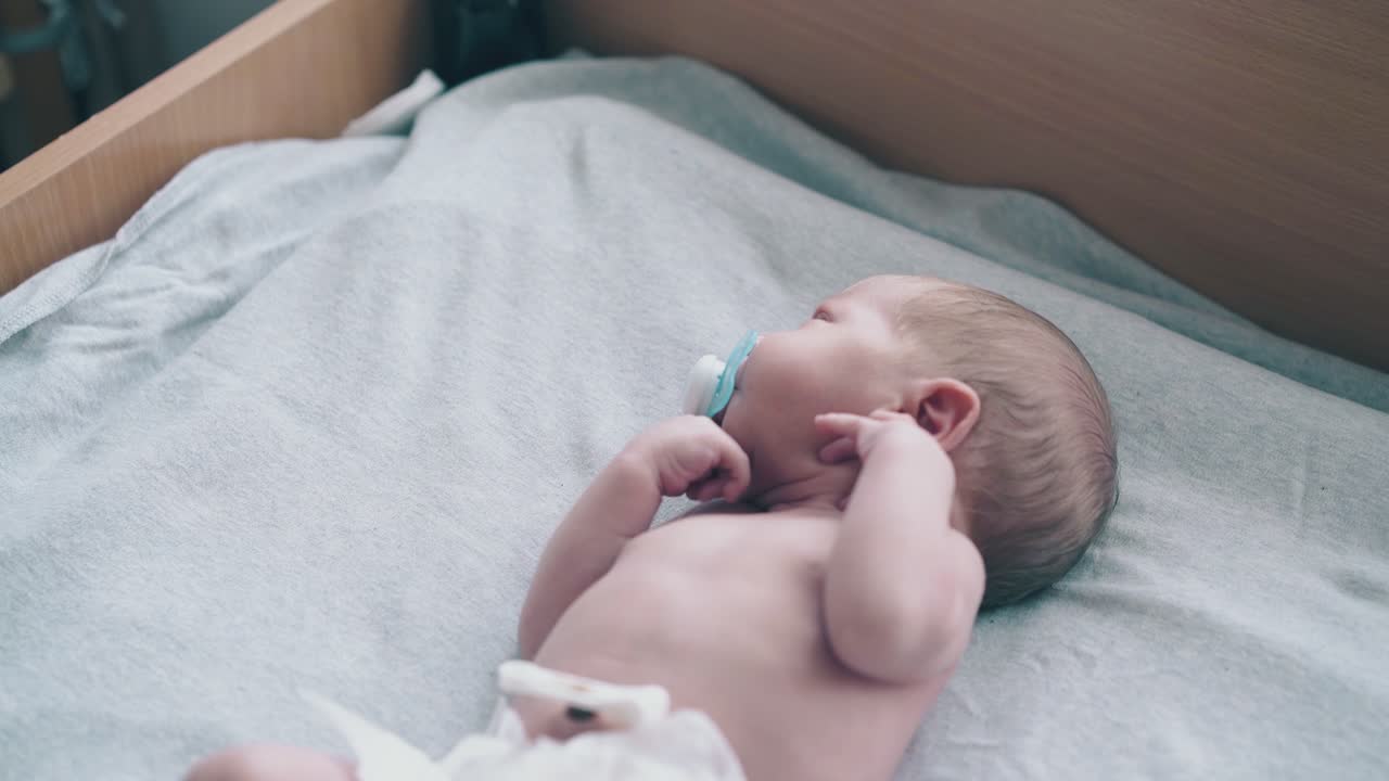 mother hand holds pacifier helping infant with short hair