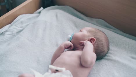 la mano de la madre sostiene el chupete ayudando al bebé con el cabello corto