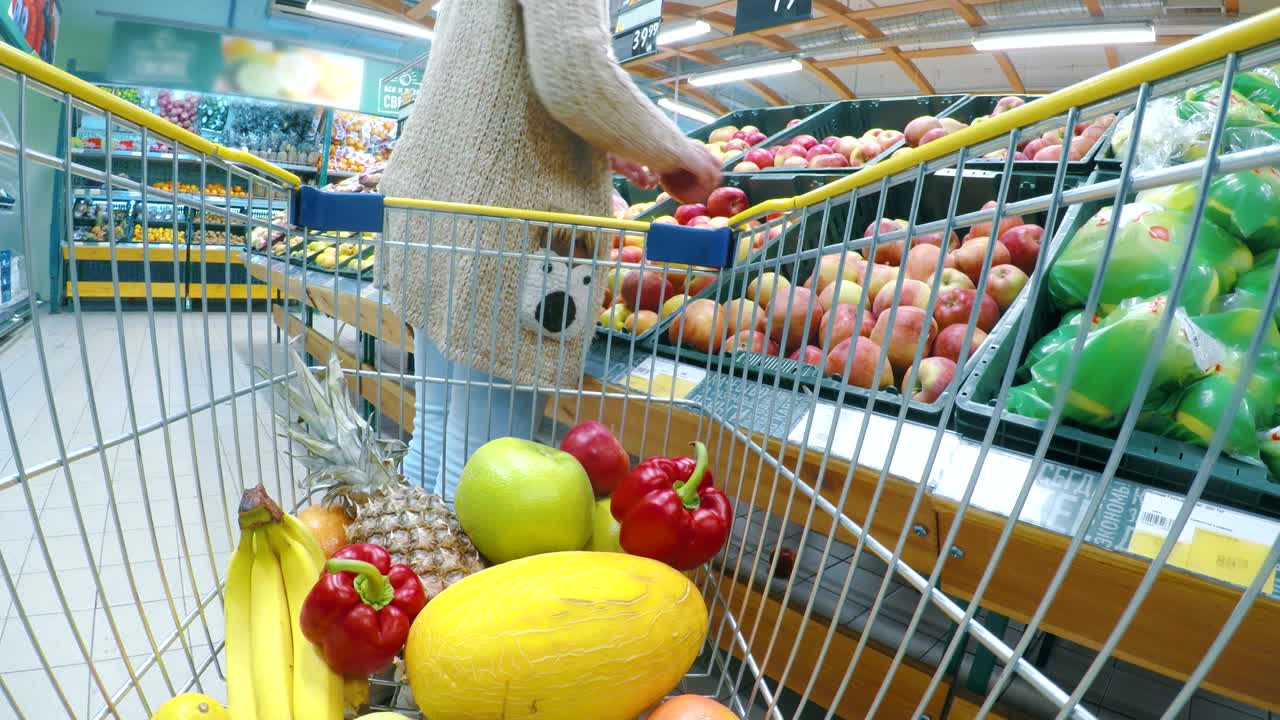 슈퍼마켓 에서 신선 한 채소 와 과일 을 구입 하는 마차 나 트롤리 를 가진 여자