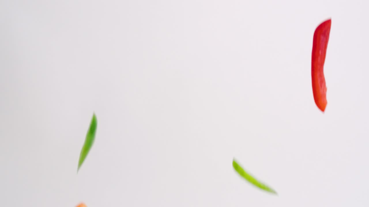 mezcla de vegetales de pimiento de colores brillantes lloviendo sobre fondo blanco en cámara lenta