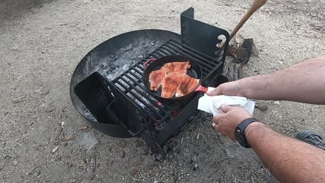 Asegurar-La-Cocción-Del-Salmón-Rojo-Cocinado-En-Una-Sartén-De-Hierro-Fundido-Rojo-Sobre-Una-Fogata