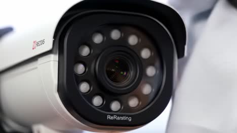 a person is carefully cleaning a security camera lens with a soft cloth in a bright area. this activity is important for maintaining high-quality video surveillance in the space.