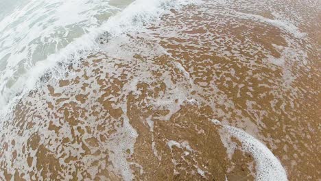 sea water receding as new wave breaks towards beach - slow motion