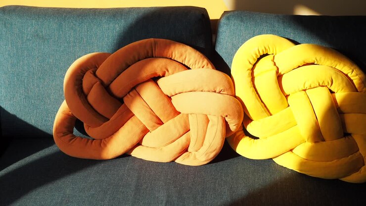 Cuscini decorativi annodati arancioni e gialli su un divano