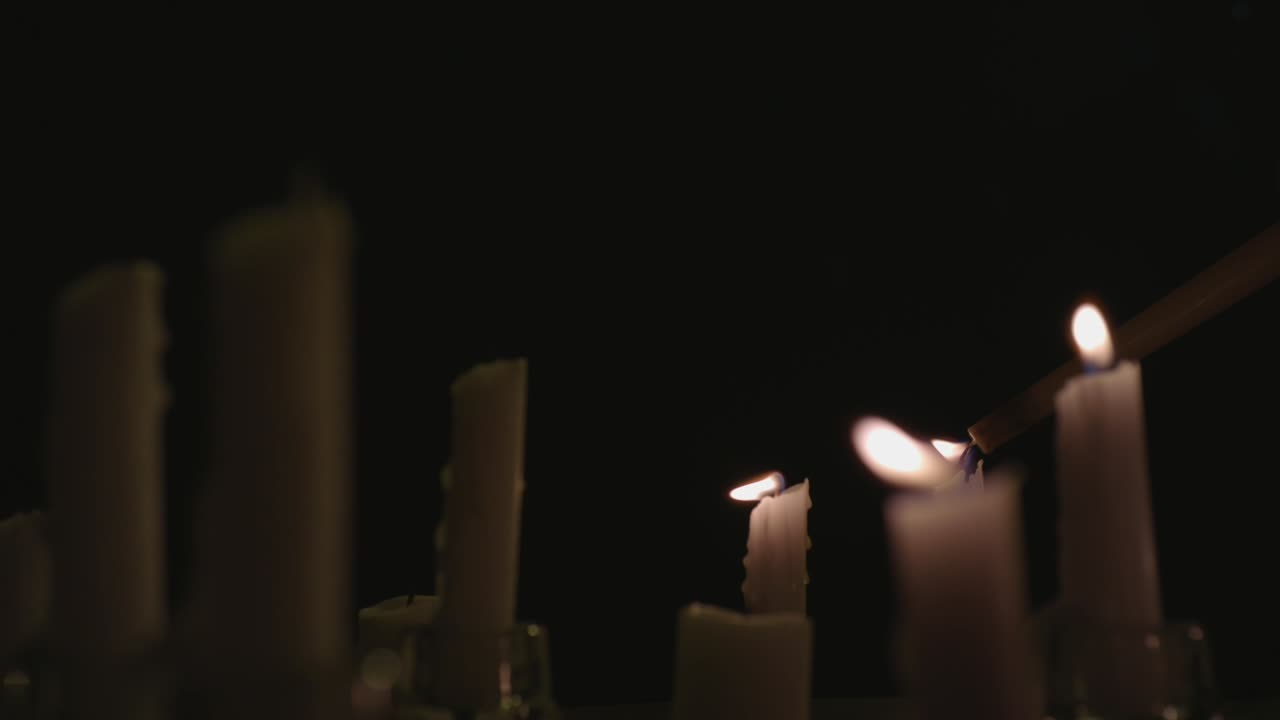 un primerísimo plano de velas blancas encendidas con un fondo negro