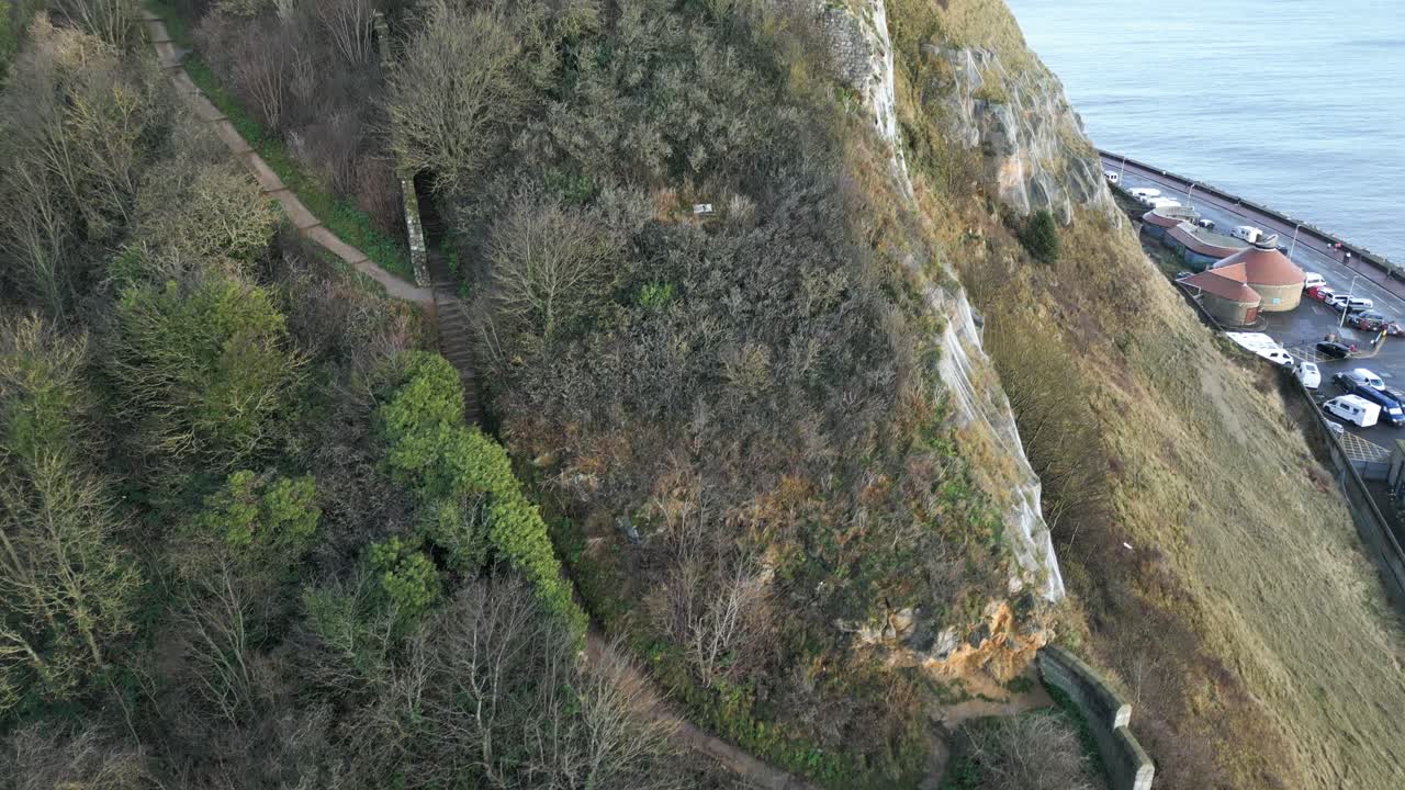 drone aéreo inclinado hacia arriba toma de escalones que conducen a las ruinas de una antigua iglesia en scarborough, north yorkshire, inglaterra