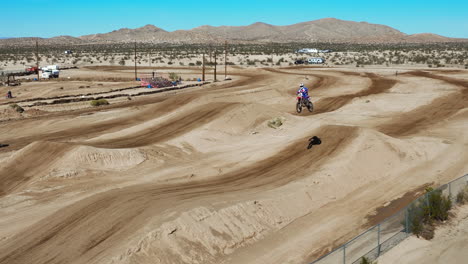 motorcycles racing on an a dirt racecourse with the mojave desert in the background - slow motion aerial view