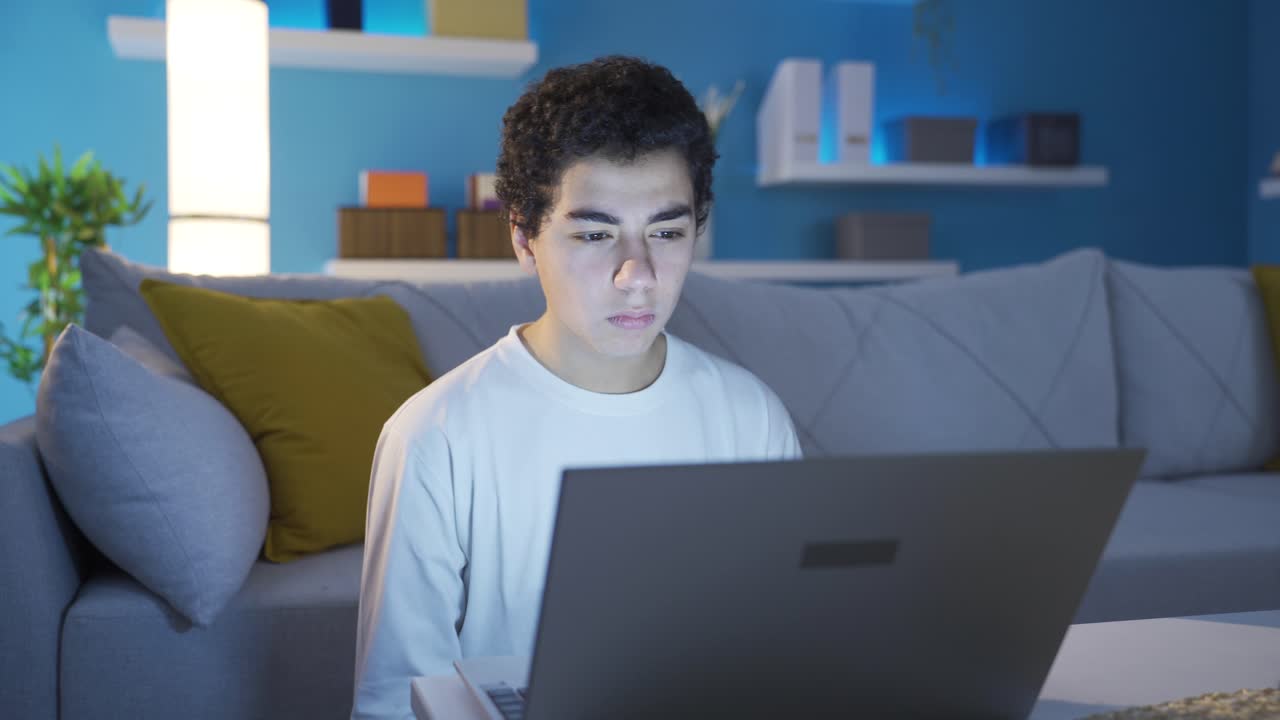 혼란스러운 소년은 혼란스럽게 노트북을 쳐다보고 있습니다.