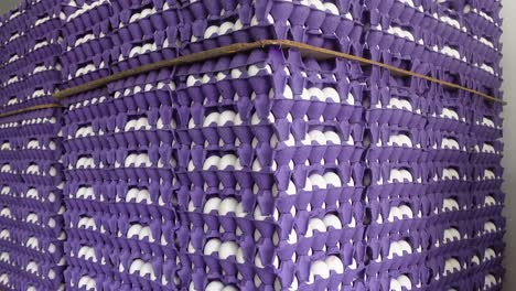 stack of purple egg cartons filled with white eggs