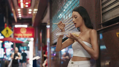 woman eating asian street food at night