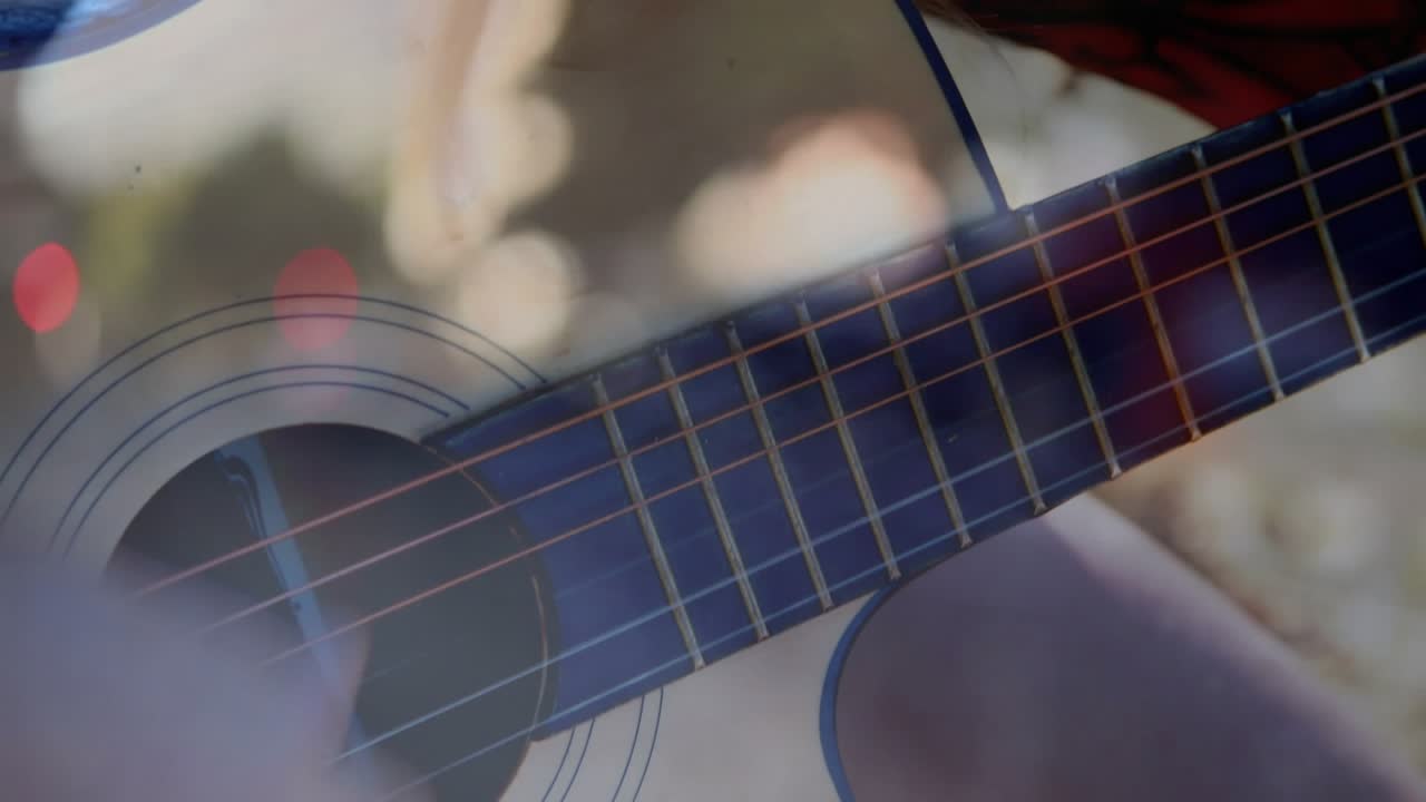 Student holding acoustic guitar, camera pulling back revealing grin, bokeh lifting music mood