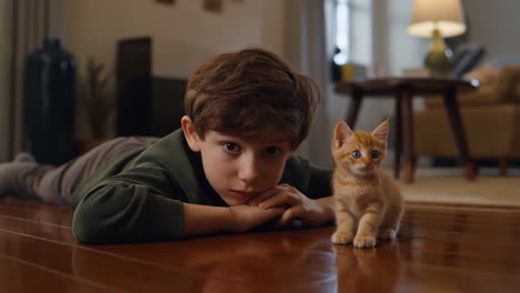 young boy and his ginger kitten on the floor
