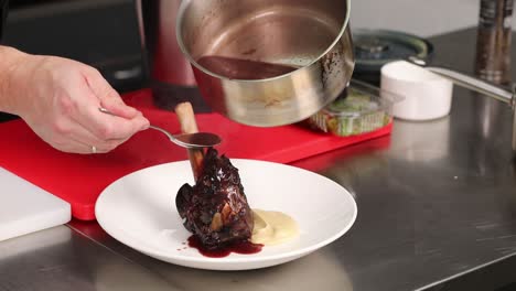 chef preparing and serving braised lamb shanks with red wine sauce