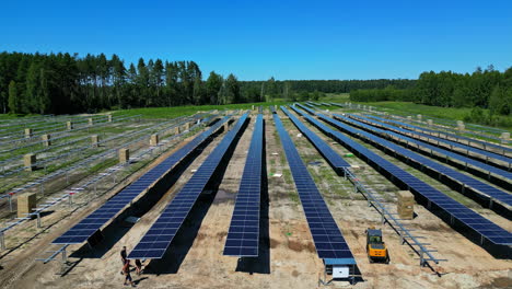 construction site new solar park with blue panels on sunny day, aerial forward