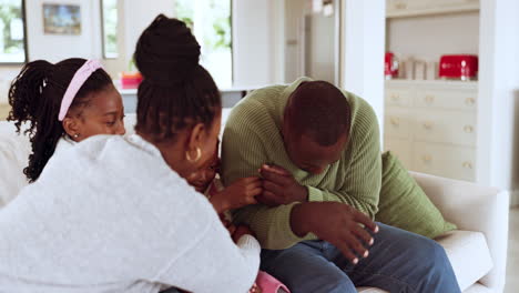 family, laughing and playing on a home sofa