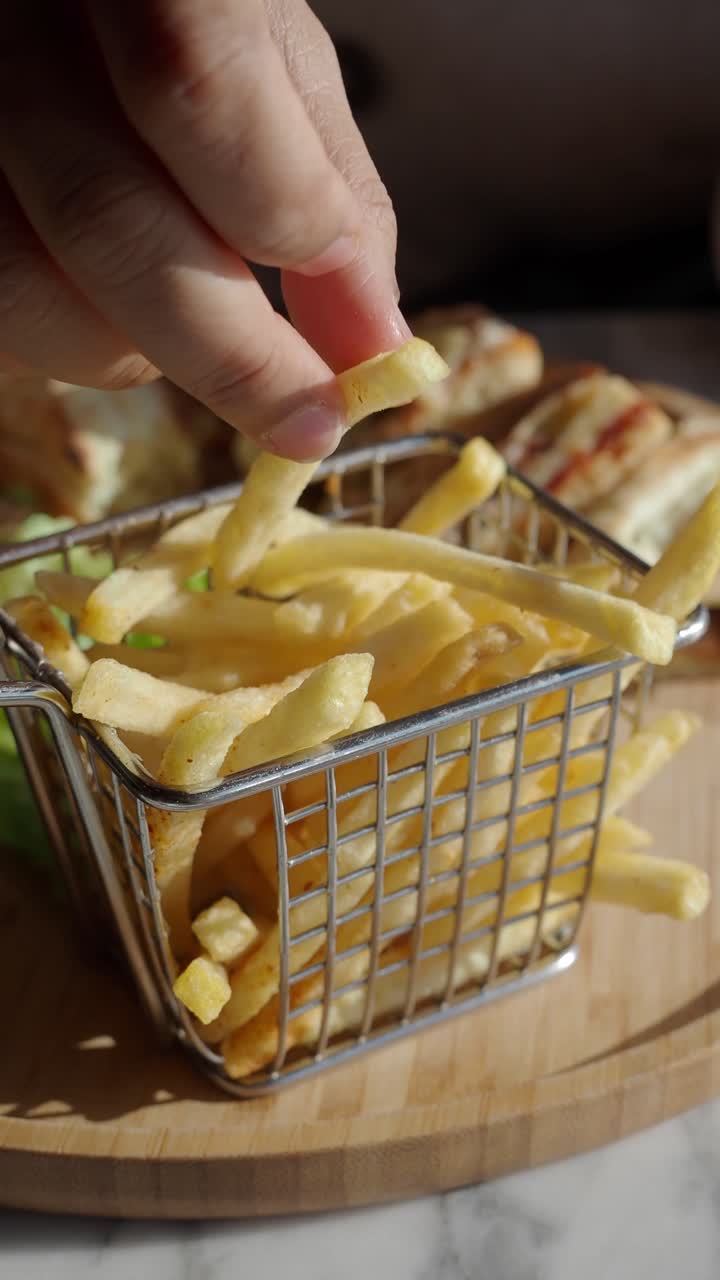 Plano Próximo de Mão Pegando Batatas Fritas Douradas de um Cesto