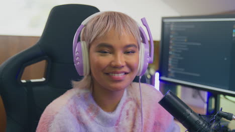 portrait of woman gaming at home sitting at desk wearing headphones for live stream