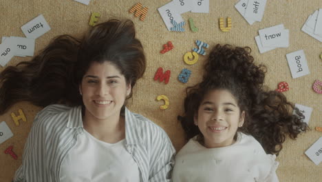 beautiful mom and daughter lying on the floor and smiling at camera