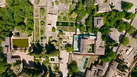 Toma-Aérea-De-Arriba-Hacia-Abajo-Del-Castillo-De-La-Alhambra-Con-Los-Jardines-Y-Edificios,-Granada,-España,-4k