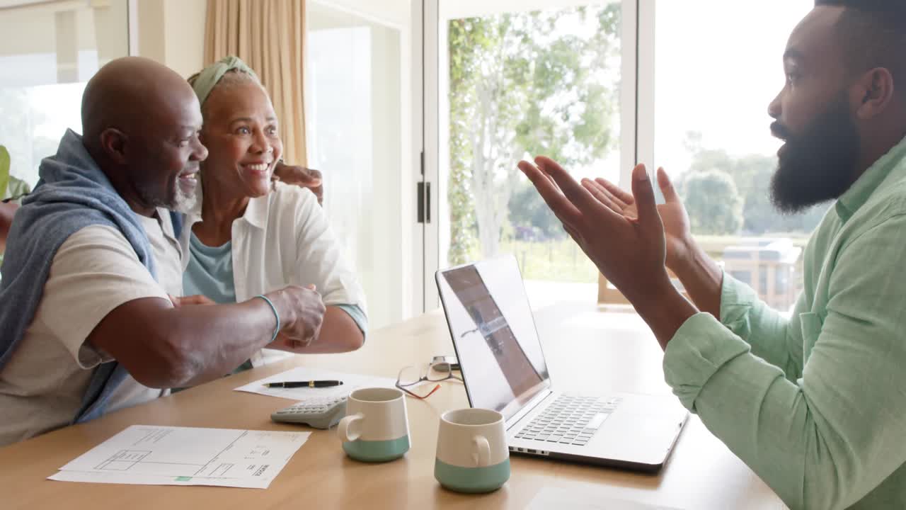 African american financial advisor and happy senior couple talking at home, slow motion