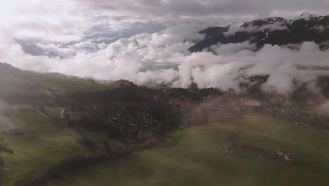 paisaje montañoso nebuloso con nubes bajas a la deriva sobre campos verdes durante el amanecer, vista aérea