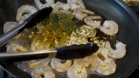 camarones chisporroteando en mantequilla y hierbas en una sartén - movimiento dinámico de comida de camarones y sémola