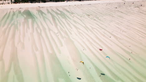 los kitesurfistas se deslizan sobre aguas poco profundas iluminadas por el sol
