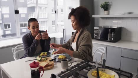 lesbian couple having breakfast in kitchen