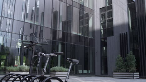 Shared-vehicles-standing-on-parking-lot-at-modern-glass-office-building-morning